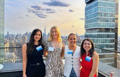 Four women smile for a photo on a rooftop during NYC Tech Week, with the city skyline and sunset in the background.